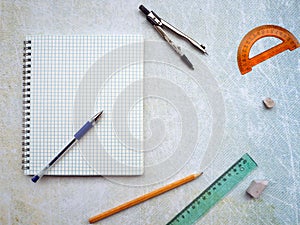 Open notebook with blank page. The compass, ruler, pencil and protractor are next to the
