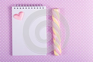 Open notebook with a blank page, marshmallow stick and little valentine on a background of polka dot