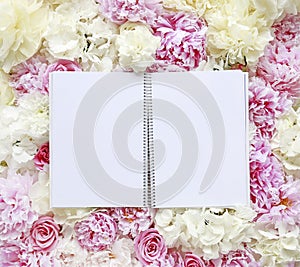 Open notebook with blank pages lying on flower background