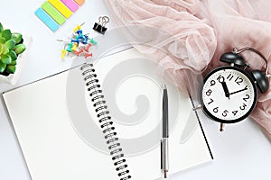 Open notebook with blank pages, pen and clock on office desk table