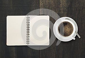 Open notebook with cup of coffee on black wooden desk. page Empty ready for your product display or montage.