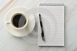 Open notebook with cup of coffee on marble desk. Workplace, work table. Top view