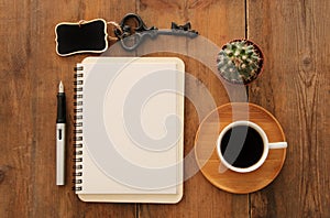 Open notebook with empty pages and other office supplies over wooden old office desk table. Top view, flat lay