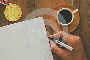 Open notebook with empty pages and other office supplies over wooden old office desk table. Top view, flat lay