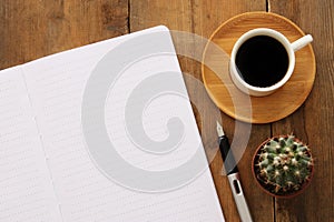 Open notebook with empty pages and other office supplies over wooden old office desk table. Top view, flat lay