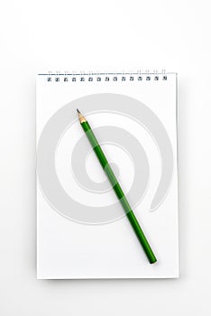 Open notebook with green Graphite pencil on white