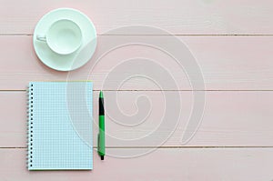 Open notebook with green pen and coffee cup