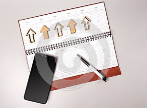 An open notebook in leather binding with a smartphone and pen on a gray background.