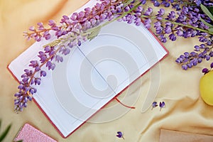 Open notebook mock up with purple lupins flowers golden background. Summer picnic. Copy space. Closeness to nature, self