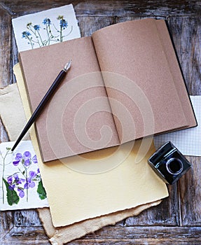 Open notebook, pen and inkwell on wooden table