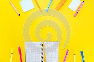 Open notebook with pen, marker and blank pages next to colorful stickers on yellow background