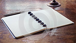An open notebook with a pen on an old wooden table