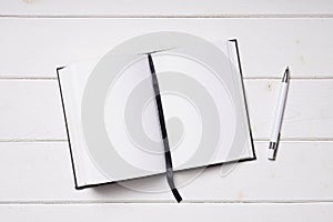 Open notebook and pen on white wooden desk