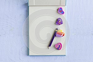 Open notebook with pencil and heart erasers on a blue background,