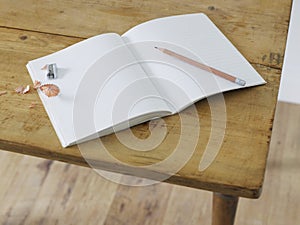 Open notebook with pencil and pencil sharpener on table elevated view