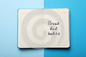 Open notebook with phrase Break Bad Habits on light blue background, top view
