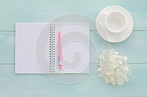 Open notebook with pink pen, coffeecup and hydrangea