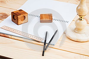 An open notebook and a ruler with two pencils and a puzzle on a wooden background.