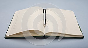 Open notebook with silver pen on office desk, side view, close up