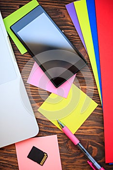 Open notebook and smartphone wooden table, top view