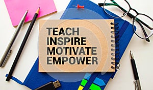 Open notebook with text Teach inspire motivate empower on wooden background