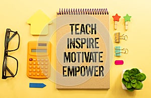 Open notebook with text Teach inspire motivate empower on wooden background
