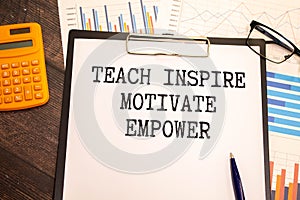 Open notebook with text "Teach inspire motivate empower " on wooden background