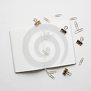 Open notebook with a white ribbon bookmark placed on a white surface