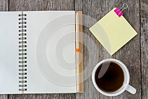 Open notebook on wooden background with coffee cup and yellow no