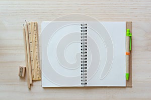 Open notebook on wooden background with pencils and ruler.