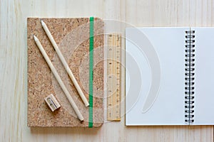 Open notebook on wooden background with pencils and ruler.