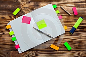 Open notepad with office supplies. Open notepad lies on a wooden desktop with marker, pencil, pen and Stickers