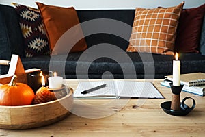 Open notepad with pen, candles and different autumn decor in modern interior