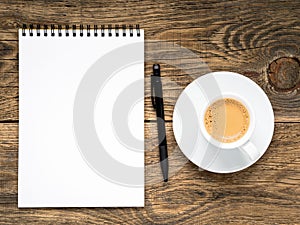 open notepad with spiral, pen and coffee cup on old wooden table