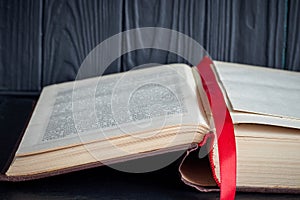 Open old book with a red bookmark on a dark background