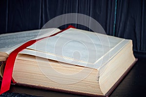 Open old book with a red bookmark on a dark background