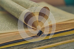 An open old book with sheets in the shape of a heart