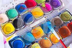 Open old palette of bright colored paints with a brush