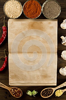 Open old vintage book with spices on wooden background. Healthy vegetarian food.