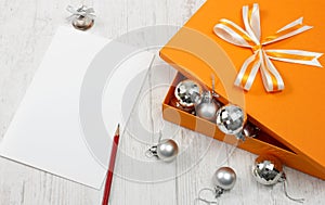 Open orange gift box with silver christmas baubles