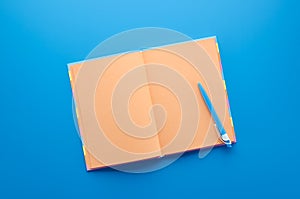 Open orange notebook with blue pens on blue background