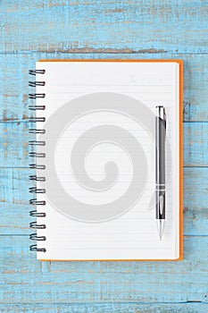 Open orange Notebook and pen on blue wood table for work