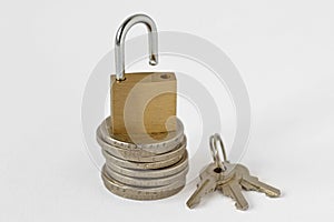 Open padlock on stack of coins with keys on white background - Concept of financial security