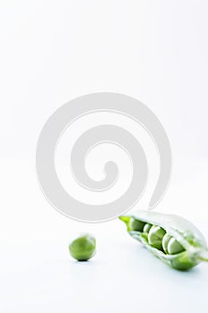 Open pea pod containing peas and single pea close-up