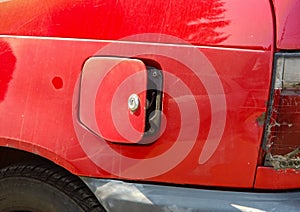 Open petrol cap on an old red car after successful theft of a gasoline or diesel fuel