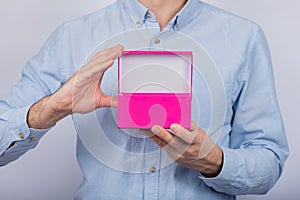 Open pink box in the men`s hands. Front view. Copy space. Mockup