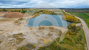 Open pit gravel mining site. Little lake or pond of unusual shape with a beautiful autumn nature and gravel piles