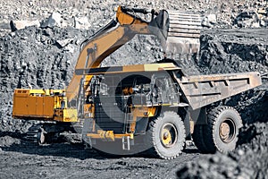 Open pit mine industry. Excavator work loading of coal into Yellow mining truck