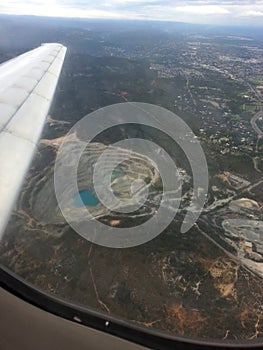 Open pit mine from plane window with wing and horizon