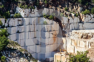 An open-pit mine of white marble stone with heavy machinery used to extract and mine the precious stone for further use